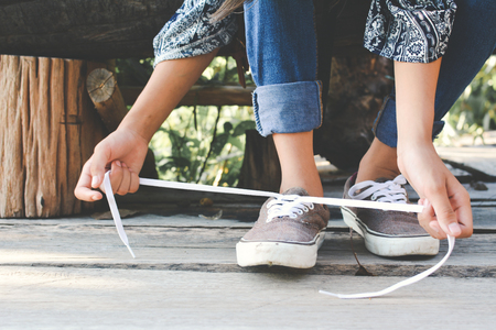 Close up girl hands tying shoelace on shoes after walkingの写真素材