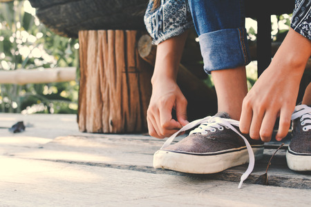 Close up girl hands tying shoelace on shoes after walkingの写真素材