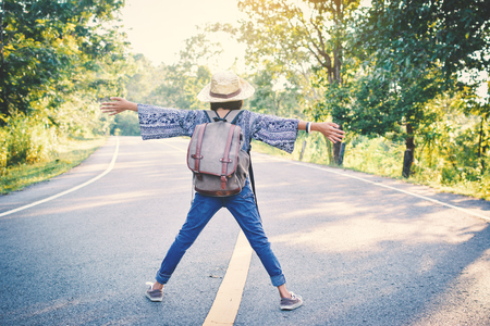 Happy Asian girl backpack in the road and forest background, Relax time on holiday concept travel ,color of vintage tone and soft focusの写真素材