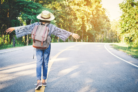 Happy Asian girl backpack in the road and forest background, Relax time on holiday concept travel ,color of vintage tone and soft focusの写真素材