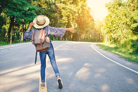 Happy Asian girl backpack in the road and forest background, Relax time on holiday concept travel ,color of vintage tone and soft focusの写真素材