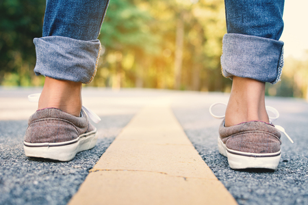 Feet of girl in the road and forest background, Relax time on holiday concept travel ,color of vintage tone and soft focusの写真素材