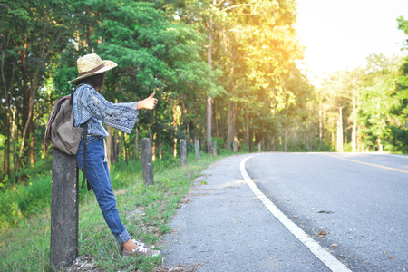 Happy Asian girl backpack in the road and forest background, Relax time on holiday concept travel ,color of vintage tone and soft focusの写真素材