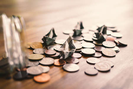 Close up dollar bird and coins in glass jar on wood table, color vintage style ,selective and soft focusの写真素材