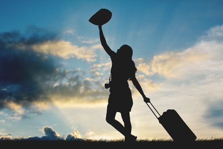 Silhouette of women travel walking with luggage at the sky sunsetの写真素材