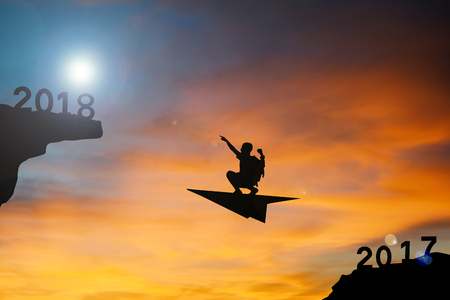 Silhouette boy flying with rocket go to 2018 word at sky sunset, concept Happy New yearの写真素材
