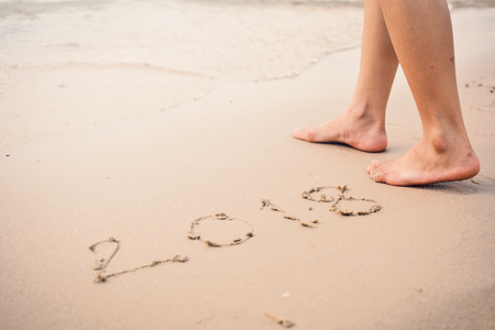 Feet women standing with 2018 word on sand, concept Happy new yearの写真素材