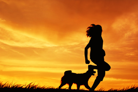 Silhouette women and dog playing at sky sunset in holidayの写真素材