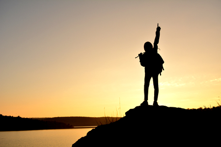 Silhouette of little girl waiting for sunset on top mountain , Happy and relax timeの写真素材