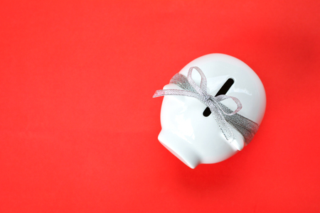 White piggy bank and ribbon type on red background with copy space ,concept save moneyの写真素材