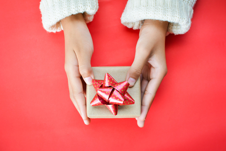 Hands of girl holding gift box on red background for Christmas conceptの写真素材