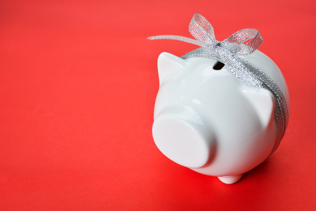 White piggy bank and ribbon type on red background with copy space ,concept save moneyの写真素材