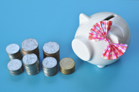 White piggy bank and coins on blue background concept save moneyの写真素材