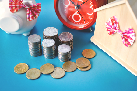 White piggy bank and alarm clock with wood house on table,concept save money ,selective and soft focusの写真素材