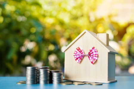 Wood house and coins on table tree bokeh background ,concept save money ,selective and soft focusの写真素材