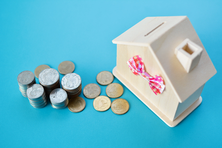 Wood house and coins on blue table background ,concept save money ,selective and soft focusの写真素材