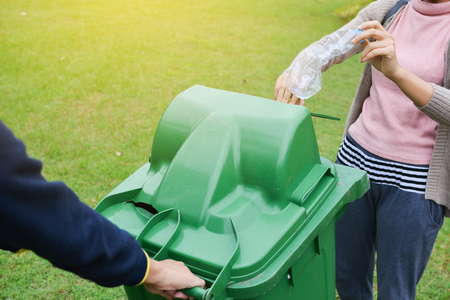 Hand of people  holding empty bottle into the trash, volunteer conceptの写真素材