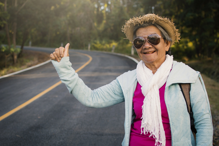 Happy hipster old women backpack traveling on the road, color vintage style selective and soft focusの写真素材