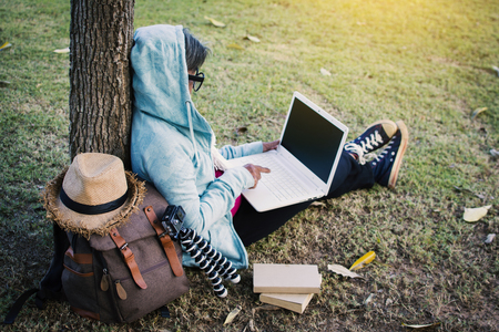 Happy hipster old women using computer in the park, relax time on holiday, color vintage style selective and soft focusの写真素材