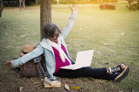 Happy hipster old women using computer in the park relax time on holiday, color vintage style selective and soft focusの写真素材