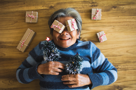 Happy old women with paper gift box  accessory on brown wood, Merry Christmas and Happy New year concept,selective and soft focusの写真素材