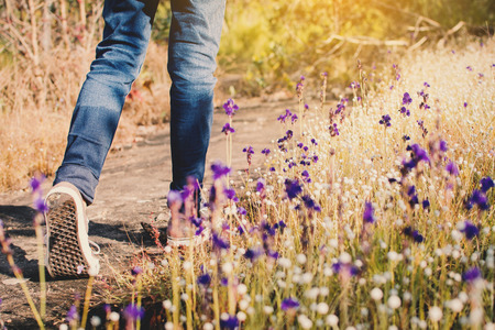 Feet of girl walking in beautiful flower filed background, Relax time on holidayの写真素材