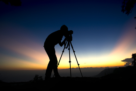 Silhouette photographer of pine trees forest with light during sunset, winter season