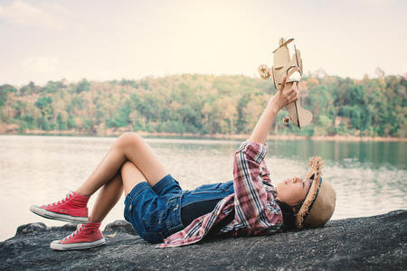 Asian girl playing wooden plane in nature , Relax time on holiday concept travel and freedom,selective and soft focus,tone of hipster styleの写真素材