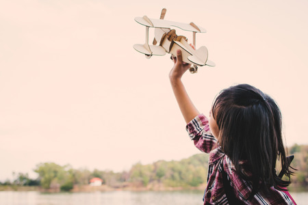 Asian girl playing wooden plane in nature , Relax time on holiday concept travel and freedom,selective and soft focus,tone of hipster styleの写真素材
