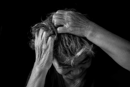 Old woman felt a lot of anxiety about hair loss and itching dandruff issue on black background, scalp problem conceptの写真素材