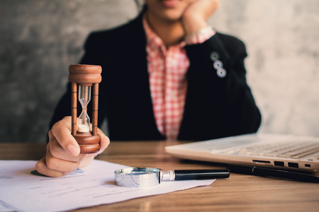 Businesswoman holding hourglass for saving time, color of vintage tone