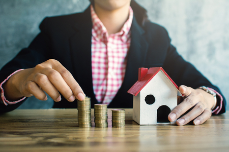 Business woman with model house and coins on desk concept saving and protect  housingの写真素材