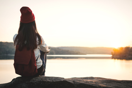 Happy Asian woman sitting on rock in nature during sunset, Relax time on holiday concept travel,selective and soft focus,color of hipster styleの写真素材