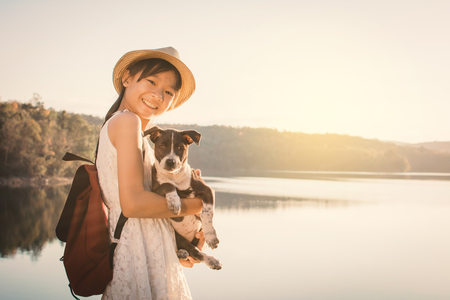 Happy girl playing with little dog in nature background, travel on holiday color of vintage toneの写真素材
