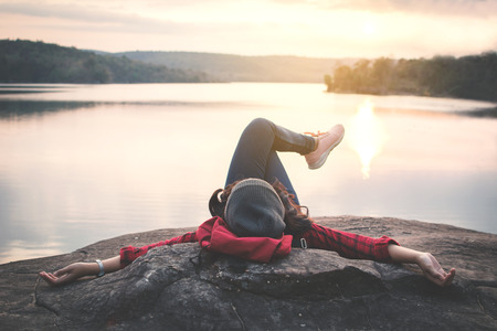 Relaxing moment Asian tourist sleeping on rock waiting for sunset, enjoying time on holiday concept, color of vintage toneの写真素材