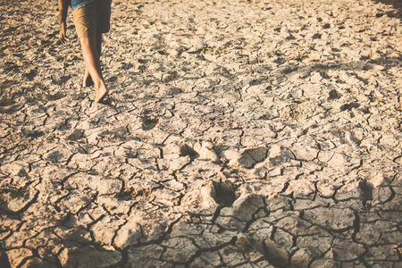 Feet of boy walking on cracked dry ground. Hope and drought conceptの写真素材