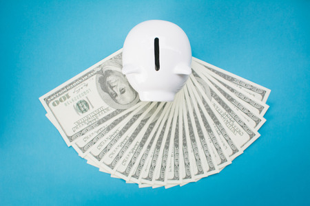 White piggy bank and money on blue background, saving conceptの写真素材