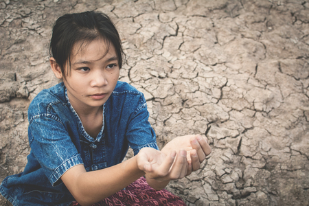 Sad girl praying for the rain on cracked dry ground , Concept drought and shortage of water crisis