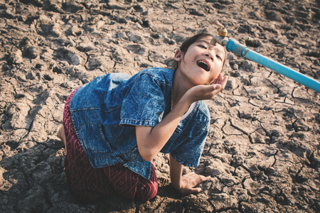 Sad girl want to drink some water on crack ground , Concept drought and shortage of water crisisの写真素材