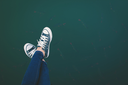 Female feet of sneaker on lake background, Rest and relaxing styleの写真素材