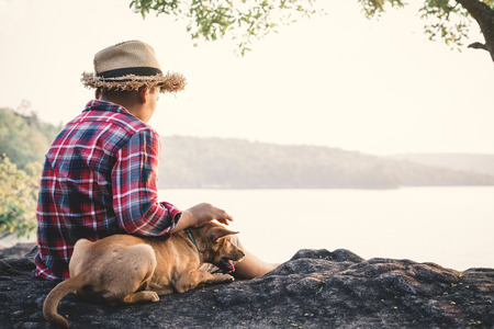 Relaxing moment Asian boy and dog in nature ,enjoying time on holiday concept ,color of vintage tone selective and soft focusの写真素材