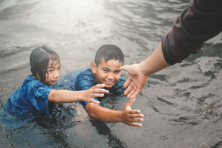 Female hand helping children in the pool