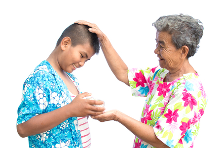Boy holding bowl of water and flower pour down to old hands woman on white background , Respect concept , Songkran festival in Thailandの写真素材