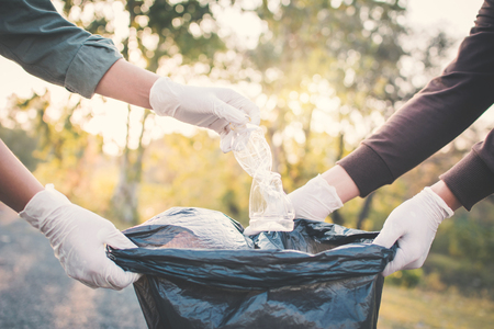Human hand picking up plastic into bin bag on park ,volunteer conceptの写真素材