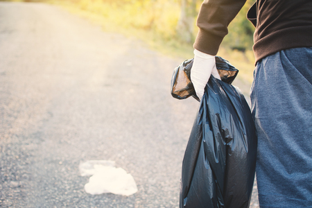 Human hand holding bin bag picking up plastic on park ,volunteer conceptの写真素材