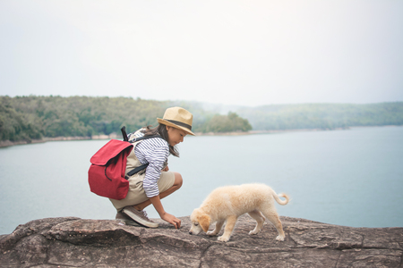 Happy girl playing with little dog in nature background, travel on holiday color of vintage tone and soft focusの写真素材