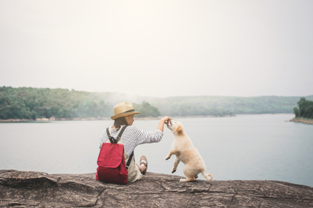 Happy girl playing with little dog in nature background, travel on holiday color of vintage tone and soft focusの写真素材