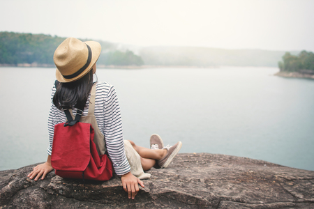 Relaxing moment Asian girl backpacker in nature ,enjoying time on holiday concept ,color of vintage tone selective and soft focusの写真素材