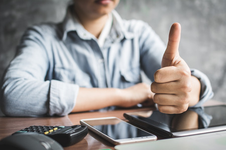 Close up hand of businesswoman thumb up with confidence on office background