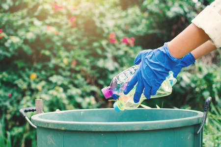 Human hand  holding empty bottle plastic garbage in to trash ,volunteer conceptの写真素材